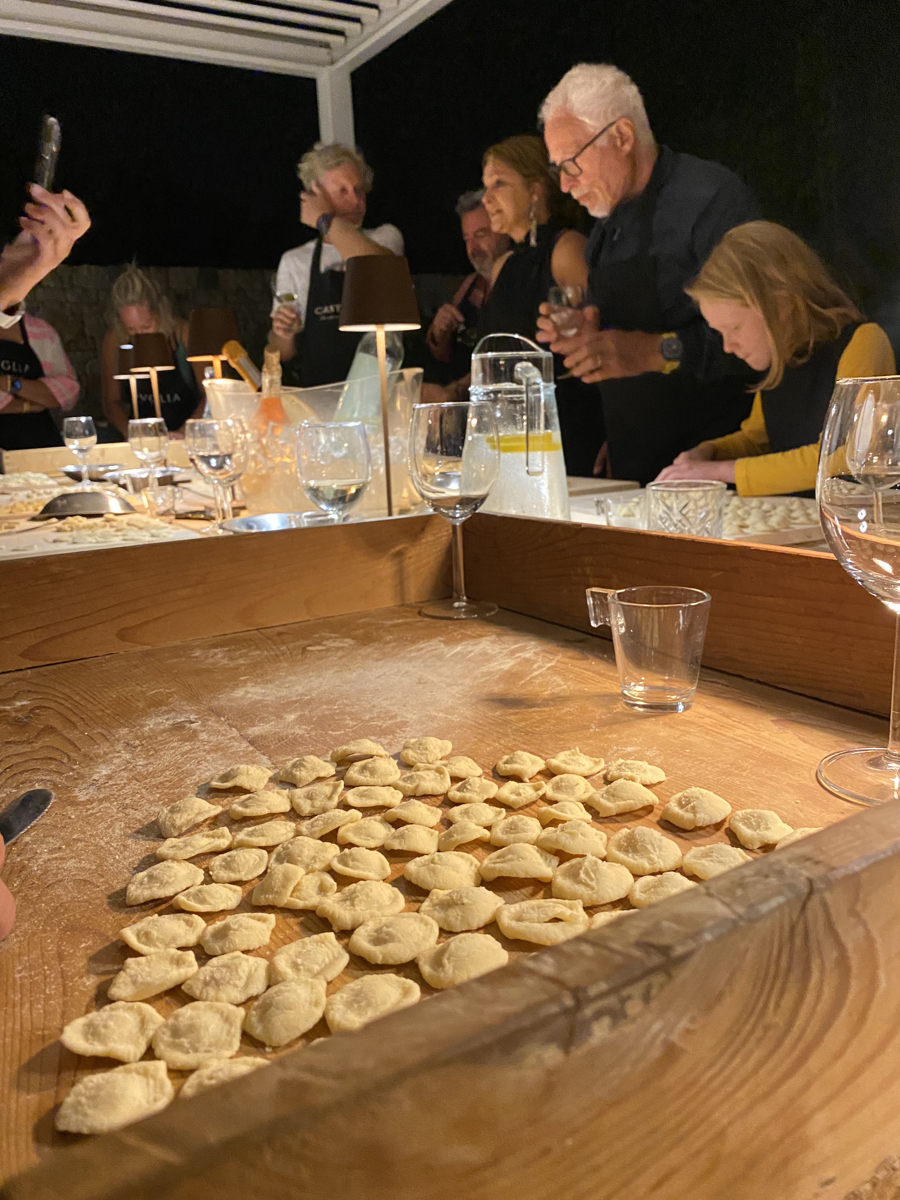 Guests shaping orecchiette under the pergola at night